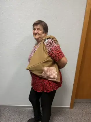 Uśmiechnięta uczestniczka z powieszoną na ramieniu uszytą torebką.