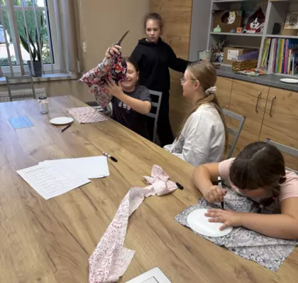 Dziewczynki wycinają z materiału koła, które posłużą do ozdabiania słoiczków