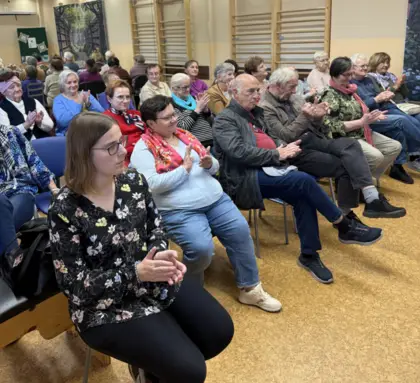 Goście zgromadzeni na spotkaniu z Ksawerą Kudlek w Bibliotece w Pawonkowie, słuchający poezji i uczestniczący w wydarzeniu.