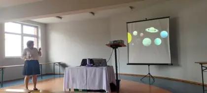 Pani z projektora wyświetla dzieciom prelekcję o kosmosie.
