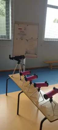 Na stoliku stoją lunety do obserwacji a w tle wiszą plakaty z projektu.