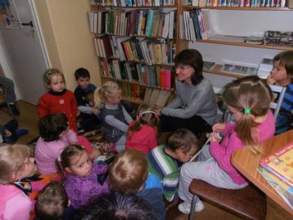 Przedszkolaki słuchają bajeczki czytanej przez panią bibliotekarkę