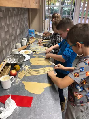 Dzieci na warsztatach kroją ciasto na makaron.