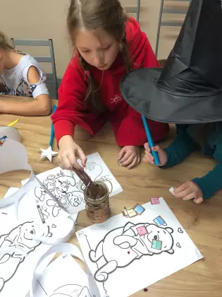 Dzieci na zajęciach literacko plastycznych. Na stole kolorowanki postaci z bajek.