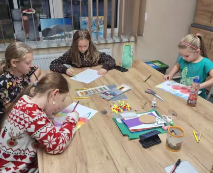 Dziewczynki malują obrazek różnymi rodzajami kredek.