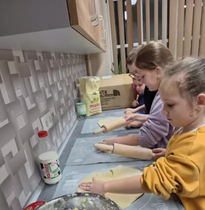 Dzieci wałkują ciasto na rogaliki.