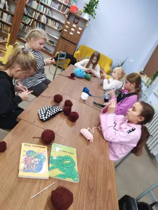 Uczestniczki szydełkują w bibliotece.