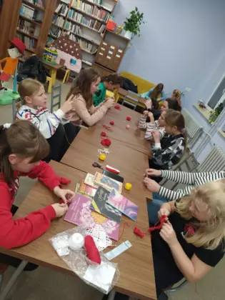 Uczestnicy szydełkują przy wspólnym stole.