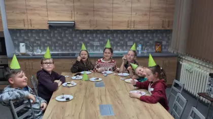 Urodzinki Zuzi. Uczestnicy siedzą przy stole i jedzą tort oraz lody.