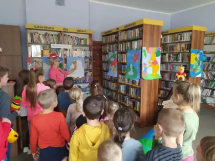 Dzieci słuchają Pani bibliotekarki, która przedstawia postacie z bajek.