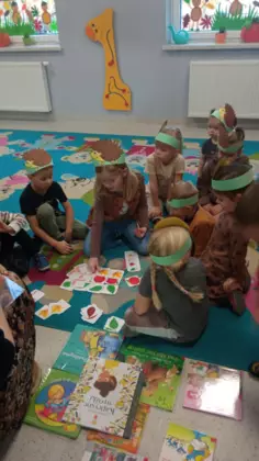 Przedszkolaki na dywanie bawią się w zabawę o jeżu.