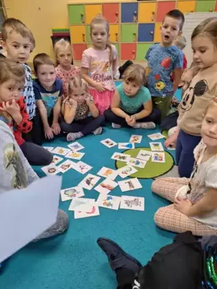 Przedszkolaki bawią się w grę sprawdzając latarką postacie z bajek.