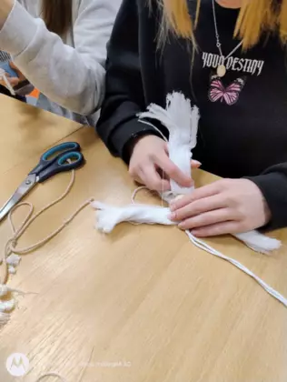 Dziewczyna tworzy aniołka metodą makramy.