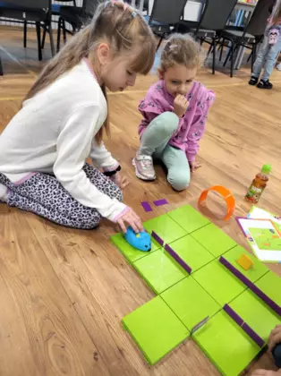Dziewczynka układa trasę dla robota myszki.