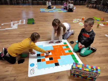 Trójka dzieci kończy kodować drzewo na macie do kodowania.