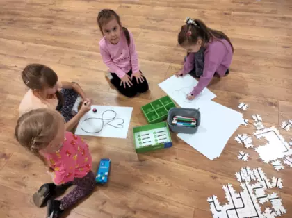 Dziewczynki rysują na kartce papieru trasę dla Ozobota.