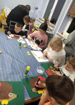 Uczestnicy zajęć malują farbami szablon jeżyka.