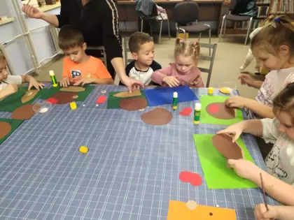 Dzieci w trakcie klejenia jeży na kolorowych kartkach.