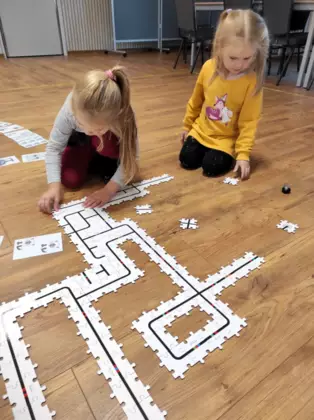 Dwie dziewczynki układają puzzle, aby wyznaczyć trasę dla Ozobota.