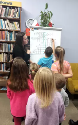 Dzieci z pomocą Pani bibliotekarki rozwiązują tematyczną krzyżówkę o Myszce Miki.