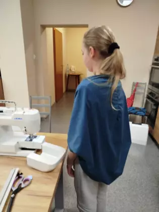 Uczestniczka zajęć ubrana w kardigan uszyty podczas zajęć z szycia.