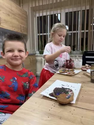 Chłopczyk i dziewczynka lukrują pierniki.