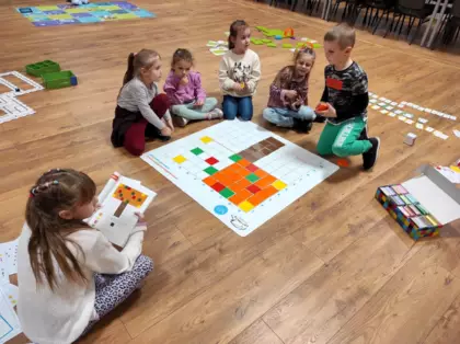 Uczestnicy zajęć układają według wzoru jesienne drzewko na macie do kodowania.