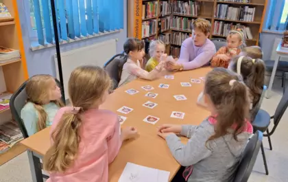 Dzieci wraz z panią bibliotekarką grają w grę.