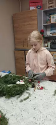 Dziewczynka  w trakcie wiązania gałązek.