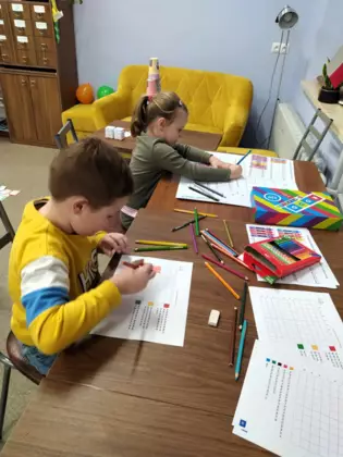 Chłopiec i dziewczynka robią kodowanki na kartce.