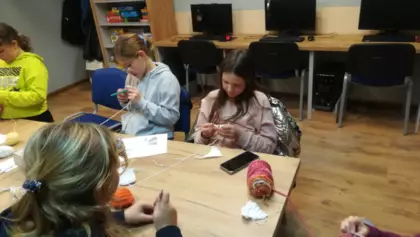 Uczestniczki zajęć szydełkują przy stole.