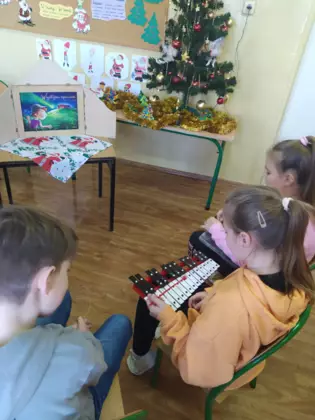 Uczestnicy grają kolędę na cymbałkach.