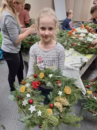 Dziewczynka pozuje do zdjęcia ze swoim wiankiem.