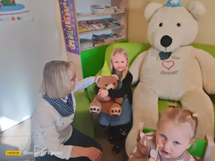 Dziewczynka pozuje do zdjęcia z wielkim misiem.