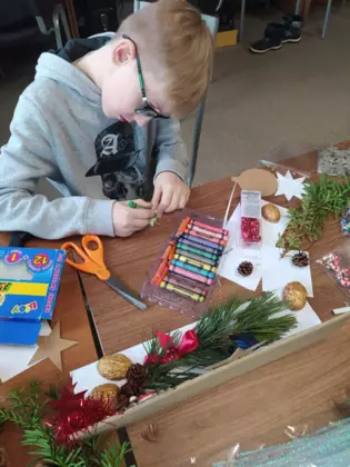 Chłopczyk wykleja świerkiem swój stroik.