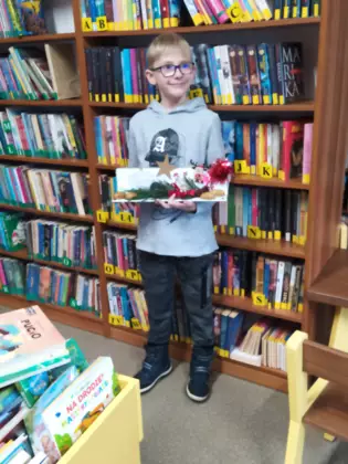 Uczestnik trzyma w ręce swoją pracę plastyczną.