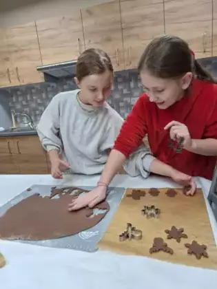 Dziewczyny wycinają z ciasta pierniki.