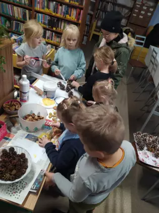 Uczestnicy wyklejają swoje stroiki zielonymi gałązkami.