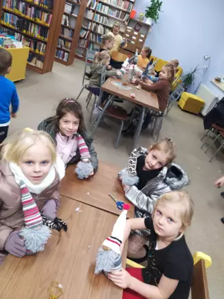 Uczestnicy szyją skrzaty w bibliotece.