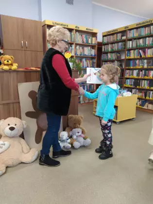 Pani bibliotekarka wręcza dyplom uczestniczce zajęć.