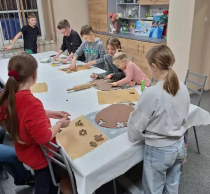 Dzieci wycinają z ciasta pierniki i układają je na blaszce do pieczenia.