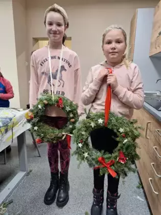Dziewczynki pokazują swoje wianki adwentowe.