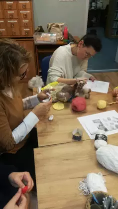 Uczestniczki zajęć szydełkowania tworzą z włóczki swoje prace.