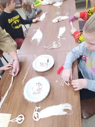 Uczestnicy wykonują aniołki ze sznurka.