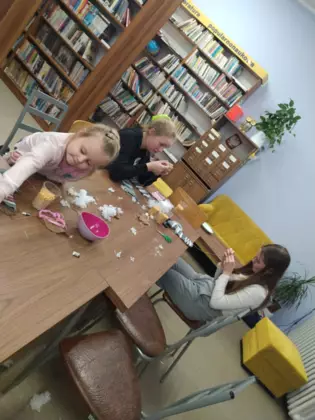 Uczestnicy szyją krasnale w bibliotece.