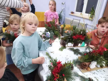 Uczestnicy wyklejają swoje ozdoby świąteczne zielonymi gałązkami.