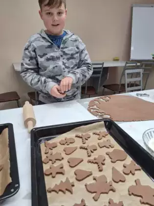 Chłopak foremką wycina pierniki z ciasta.