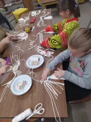 Uczestnicy wykonują aniołki ze sznurka.