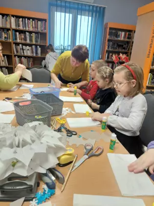 Uczestnicy sklejają torebki papierowe.