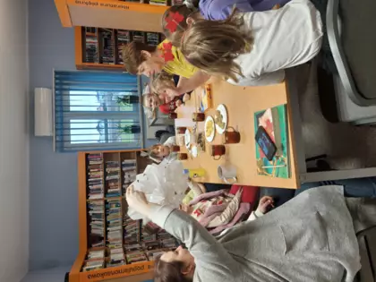 Uczestnicy zajęć jedzą pierniczki, piją herbatkę i śpiewają świąteczne piosenki.